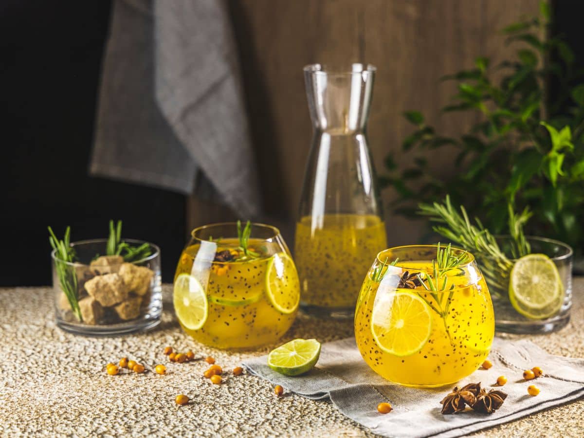 A glass of chia seed lemonade with rosemary and ginger on a wooden table.