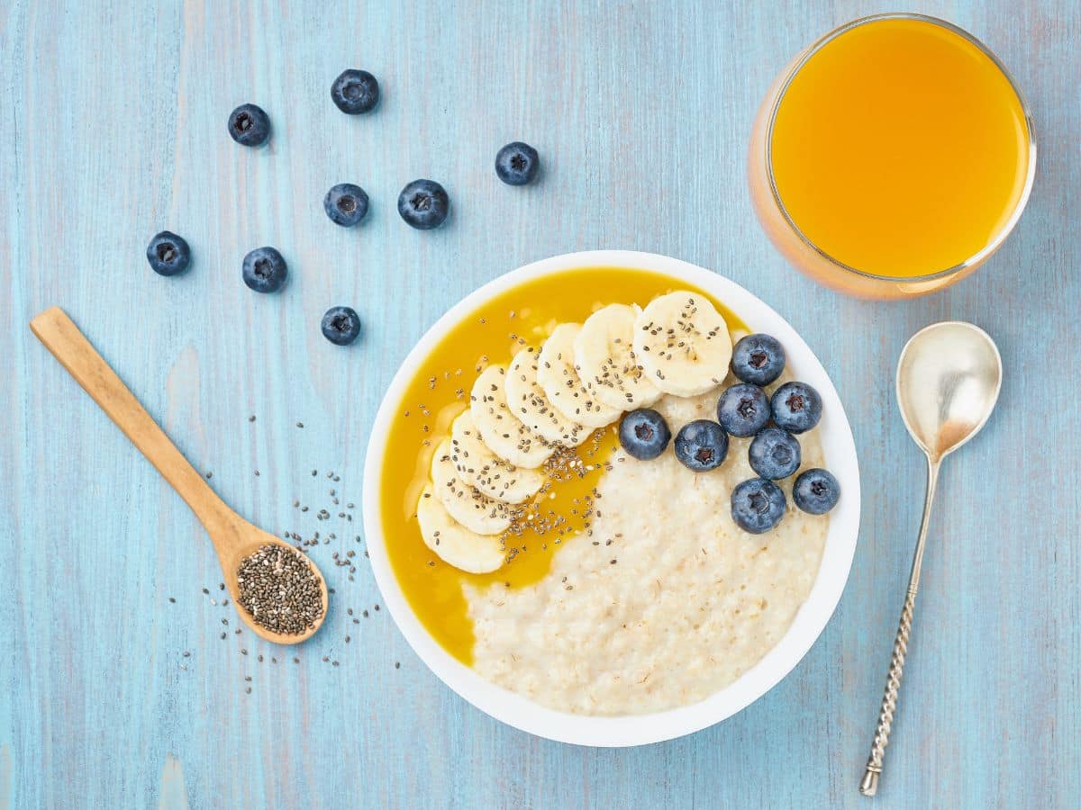 A bowl of oatmeal topped with sliced bananas, fresh blueberries, and a sprinkle of chia seeds.