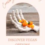 A 3D-printed skeleton hand holds candy corn and pumpkins on a wooden surface. Text reads: "Craving Candy Corn? Discover Vegan Options.