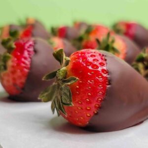 Rows of delicious chocolate covered strawberries on a sheet of parchment paper.