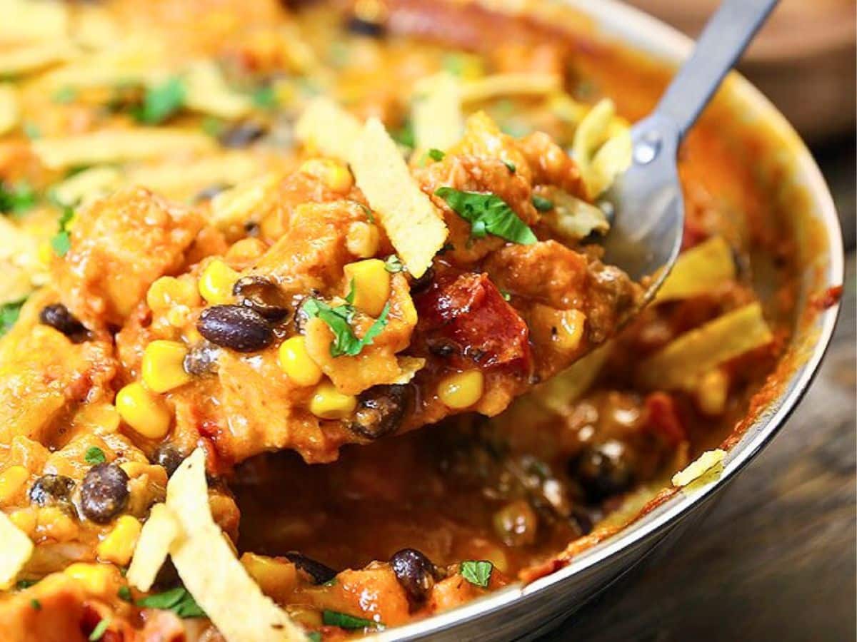 A close-up of a cheesy casserole with corn, black beans, and tortilla strips.