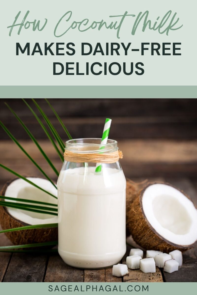 A glass jar of coconut milk with a green-striped straw is placed on a wooden surface, surrounded by coconut halves and coconut pieces.