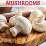Several white mushrooms on a wooden cutting board with the text "How to Freeze Mushrooms" at the top.