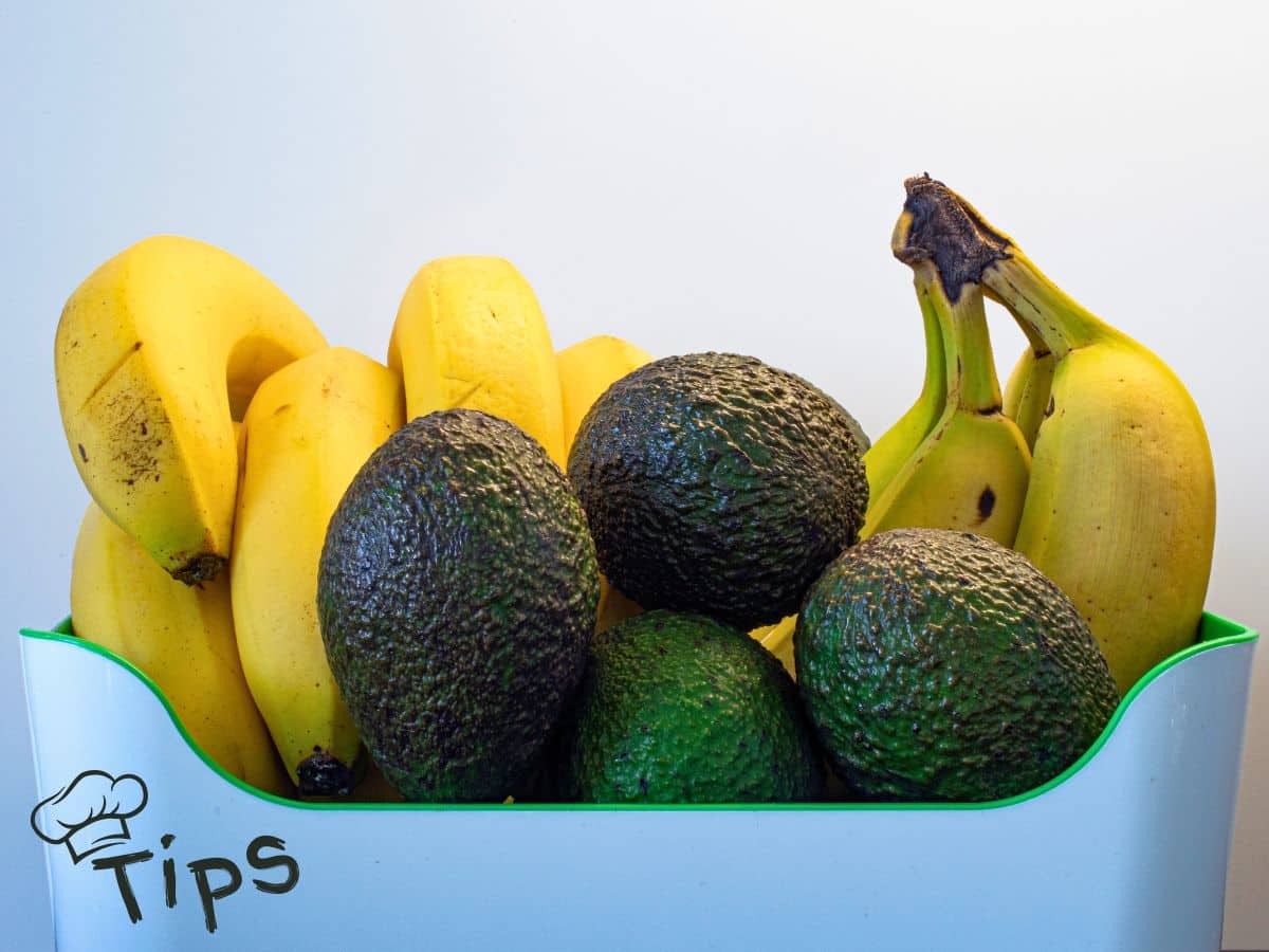 A basket filled with ripe bananas and avocados against a plain background.