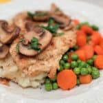 A plate of Chicken Marsala topped with mushrooms, served with mashed potatoes, peas, and carrots. Text overlay reads, "The perfect CHICKEN MARSALA.