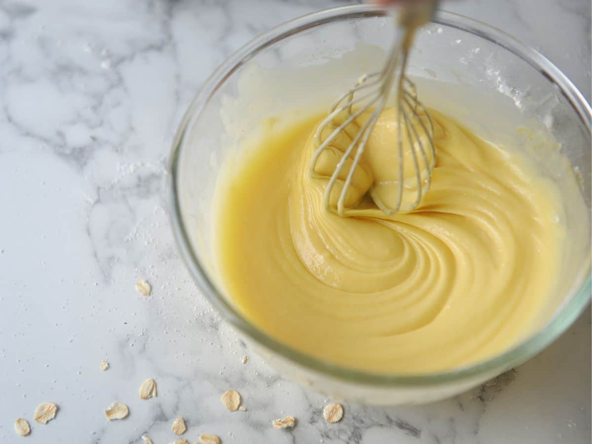 Woman whisking cake batter in a glass bowl.