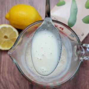 A spoonful of vegan buttermilk with the ingredients in the background.