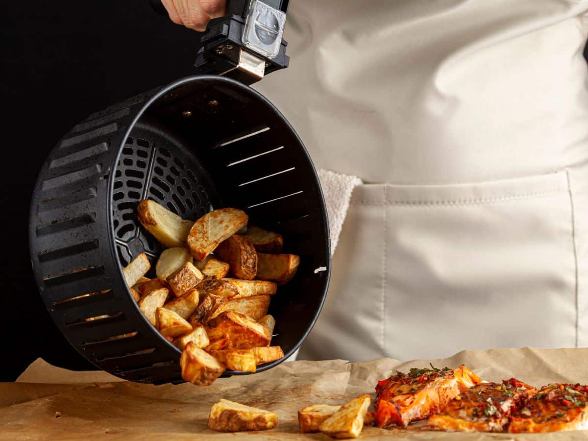 A home chef pouring potatoes out of an air fryer