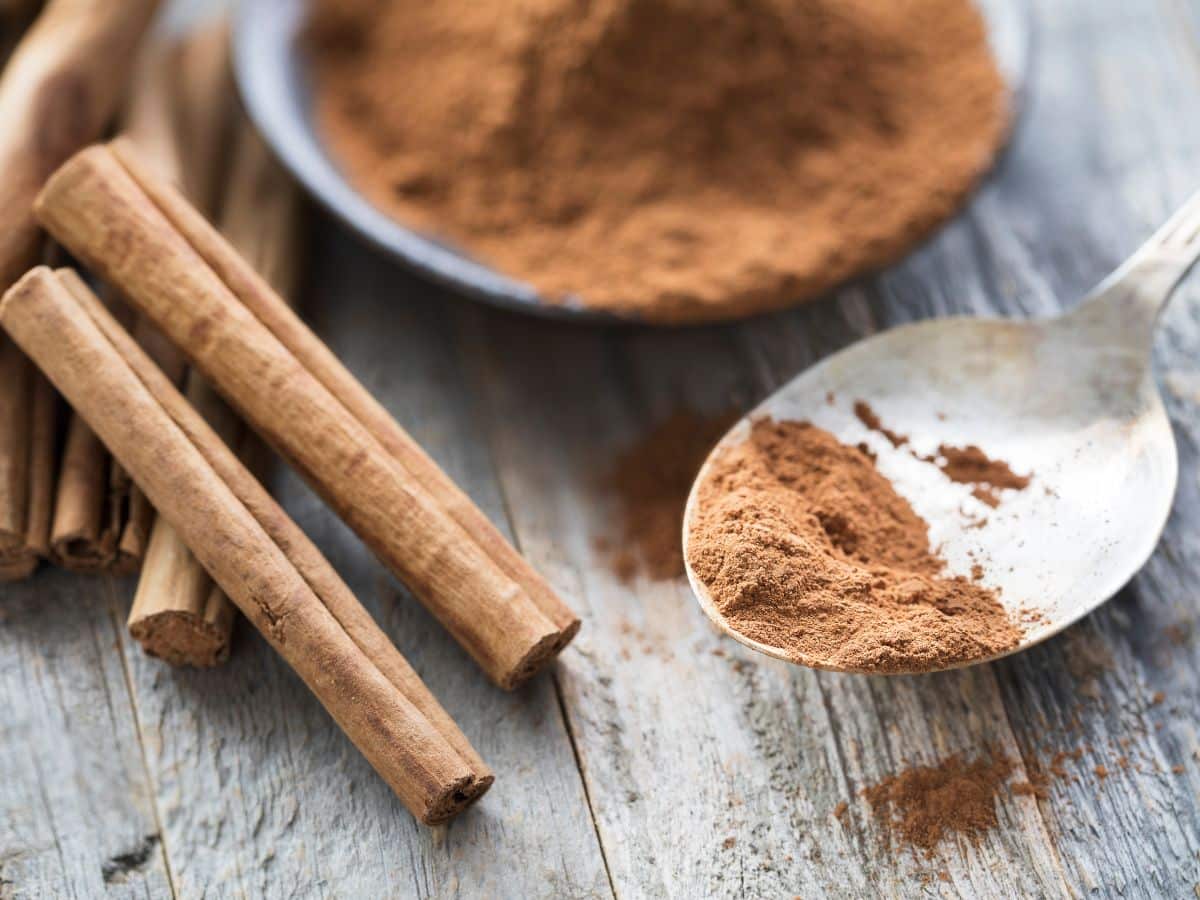 Cinnamon powder and cinnamon sticks on a wooden table.