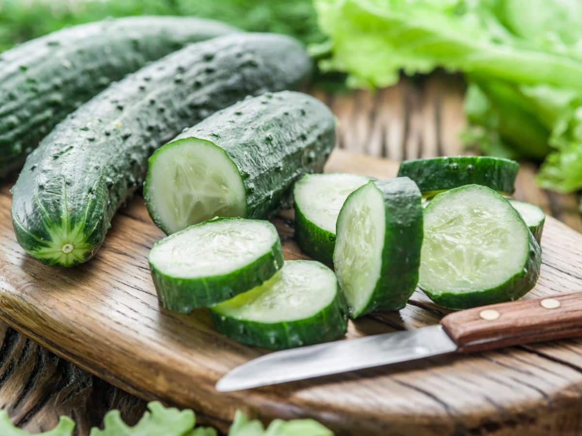Cucumbers and a knife on a cutting board.