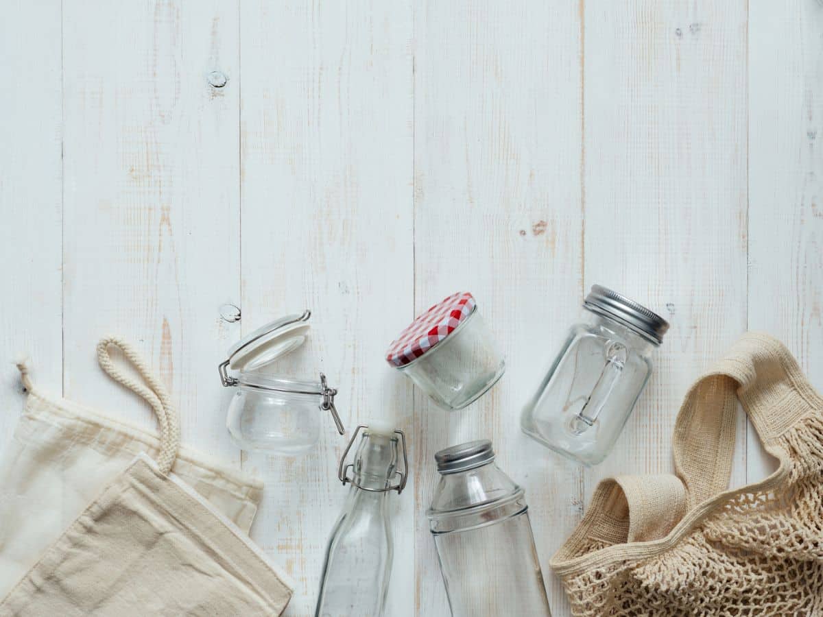 Glass jars and a bag on a white wooden table.