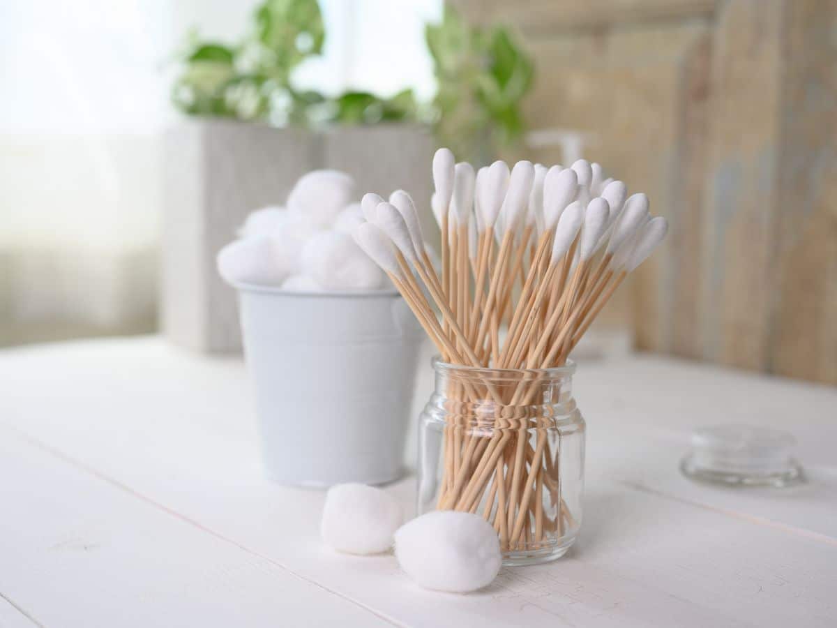 White cotton swabs in a jar on a wooden table.