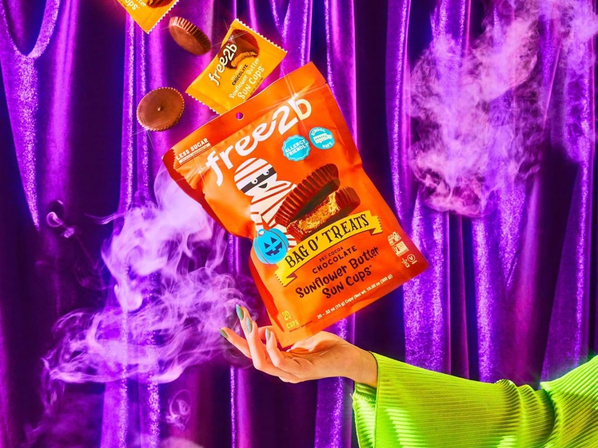 A woman is holding a bag of Halloween themed sunflower butter cups.