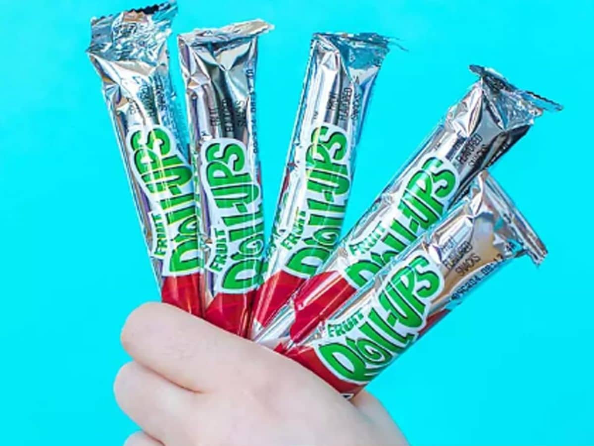 A child's hand holding Fruit Roll-Ups in silver packaging.