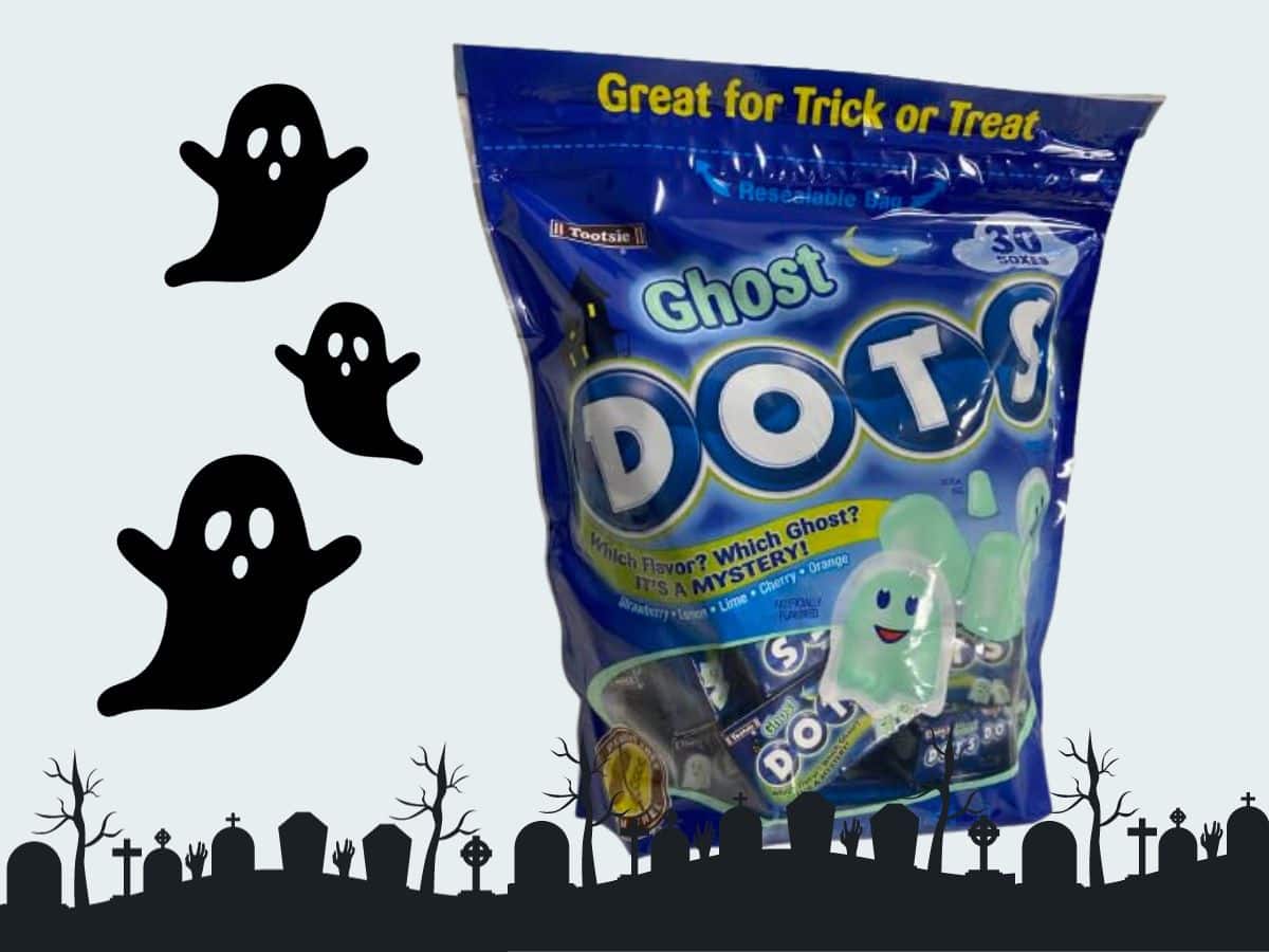 A bag of ghost dot candy in front of a graveyard.