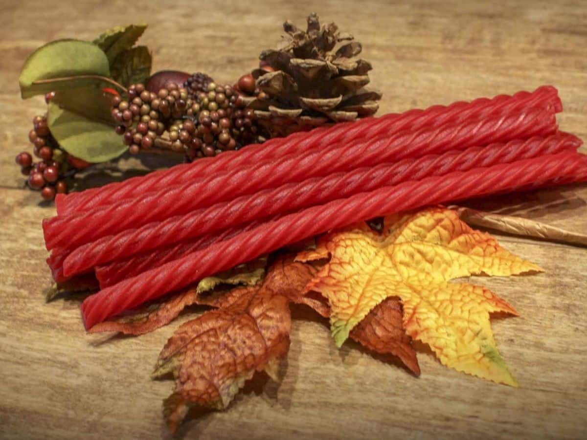 A bunch of red licorice sticks on a wooden table.