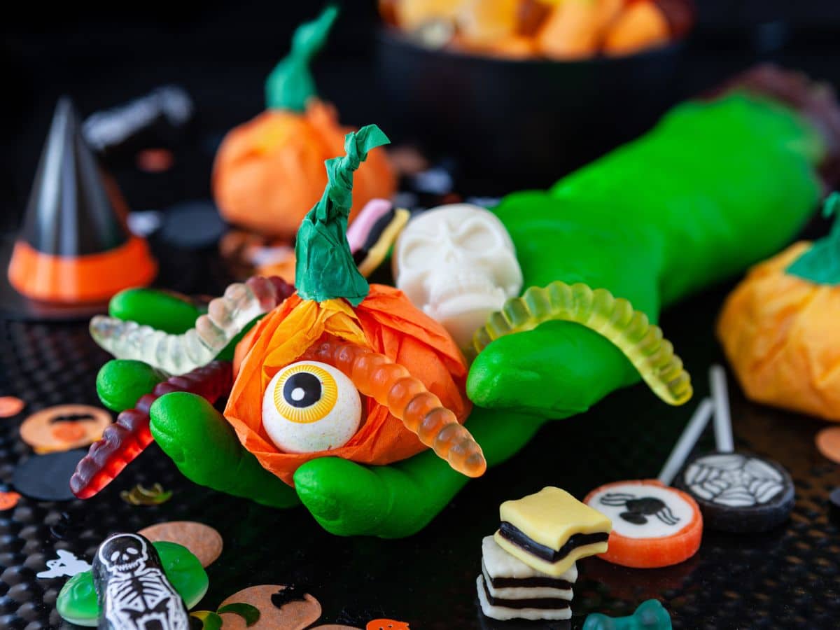 A hand covered in candy and halloween decorations.