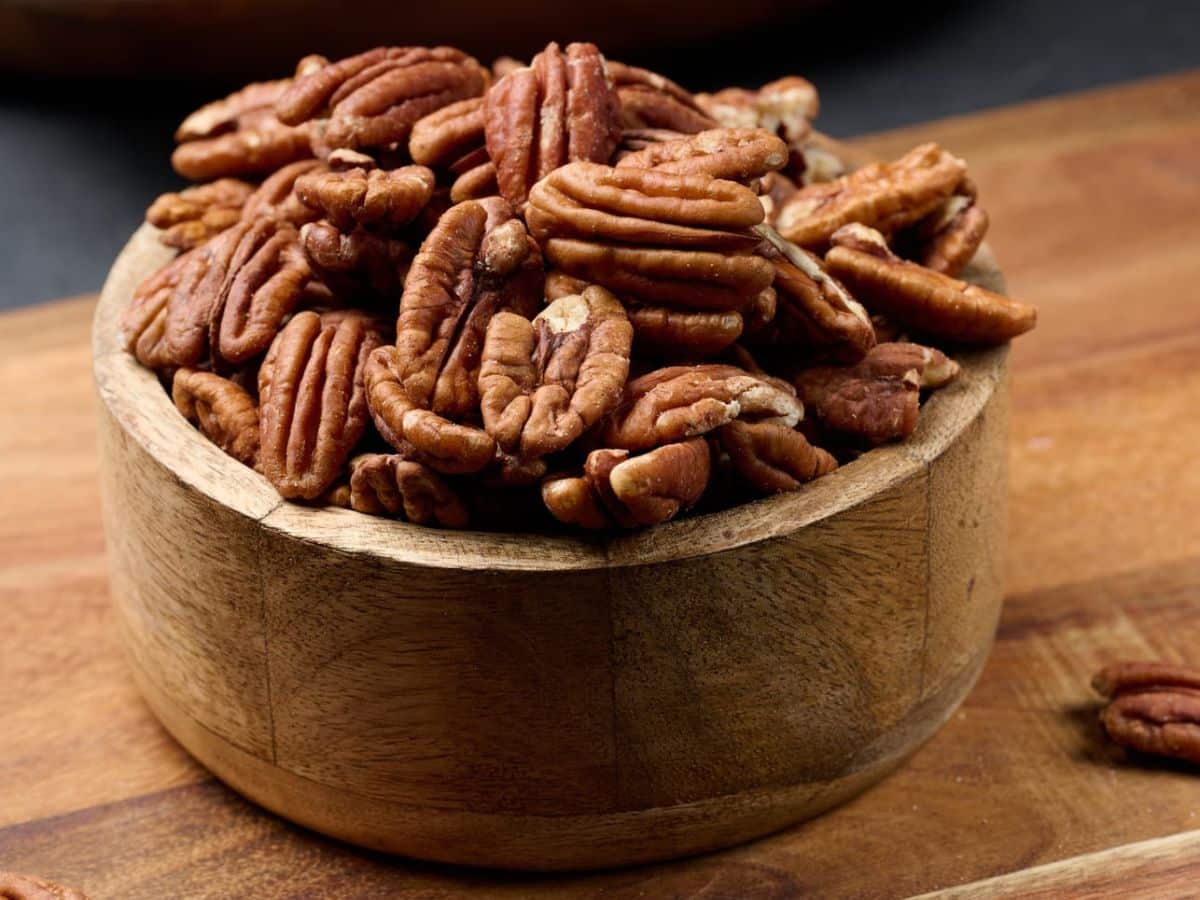 Pecans in a wooden bowl on a wooden table.