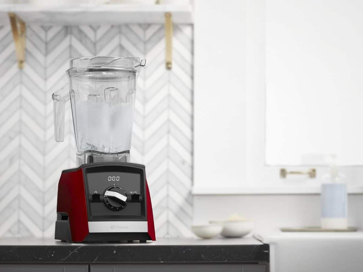 A red Vitamix A3500 blender on a counter in a kitchen.