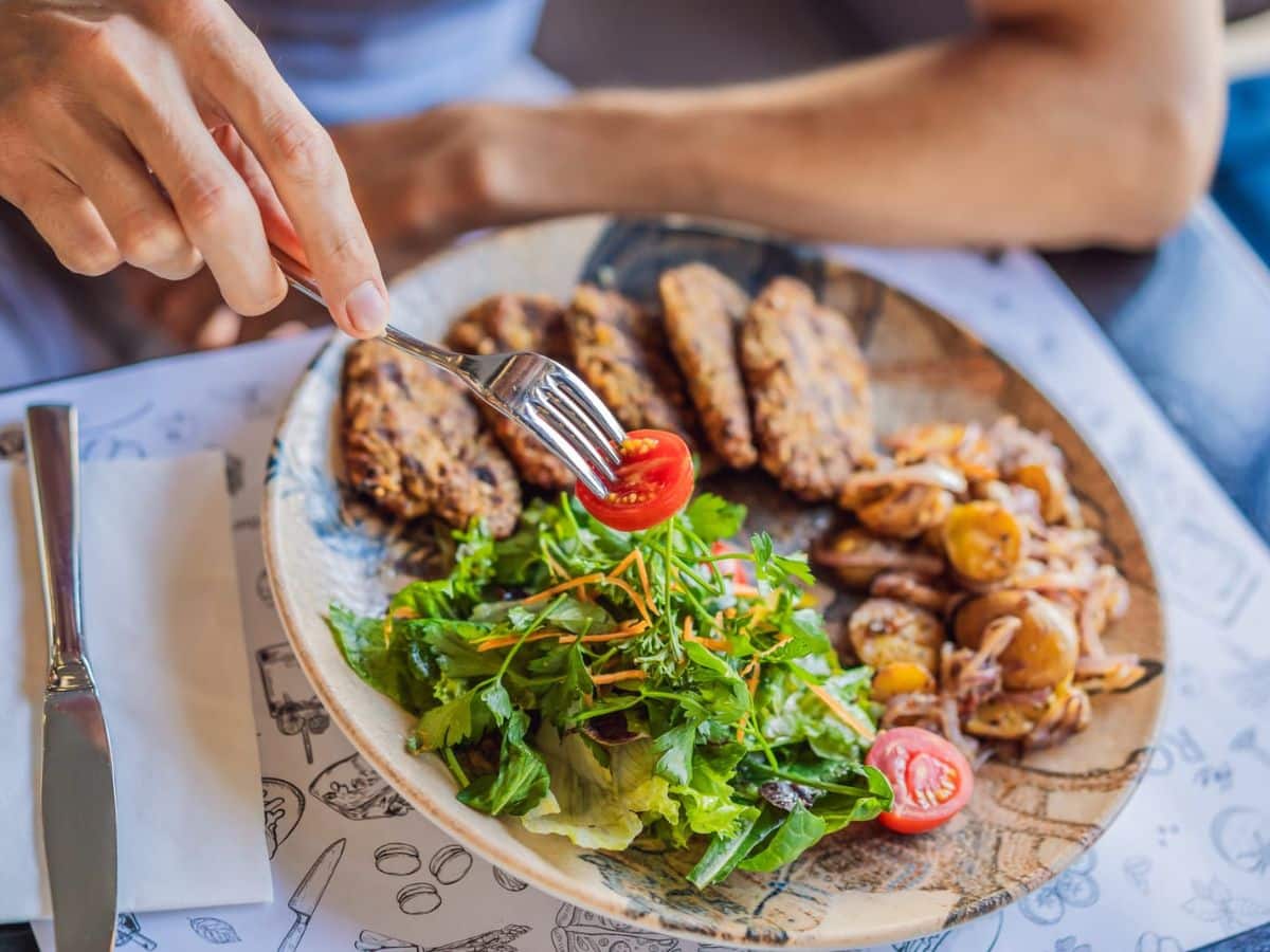 A person eating a plate of food with a fork.