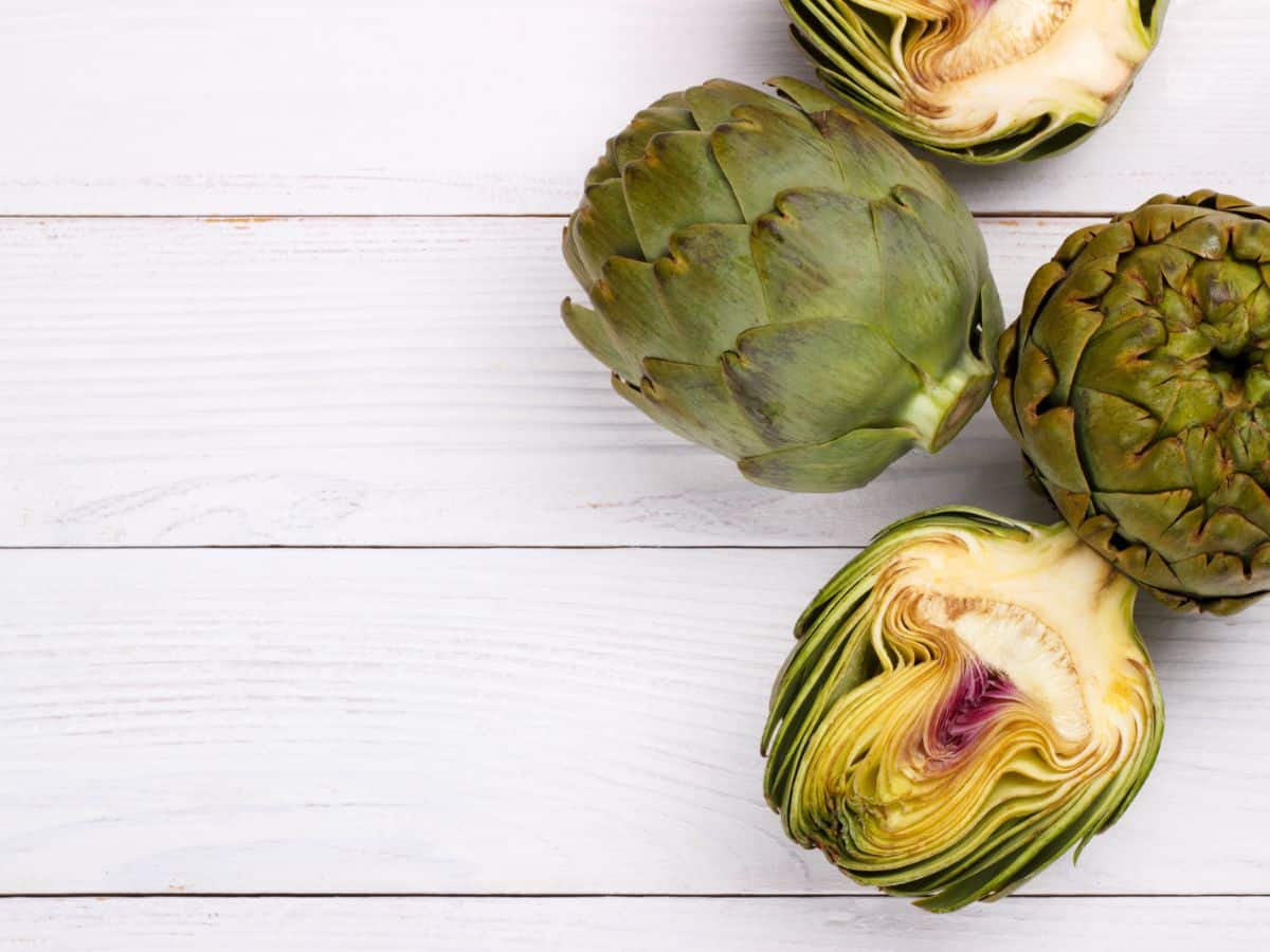 Artichokes on a white wooden table.