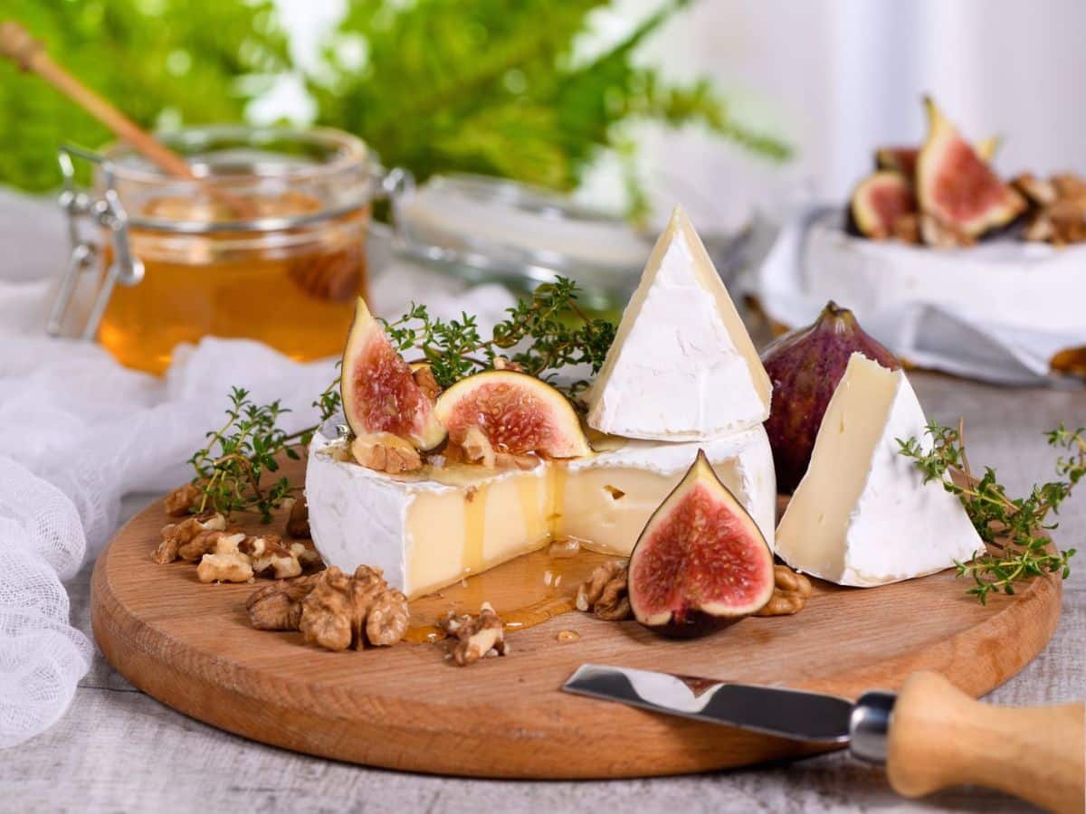 Cheese with figs and honey on a wooden board.