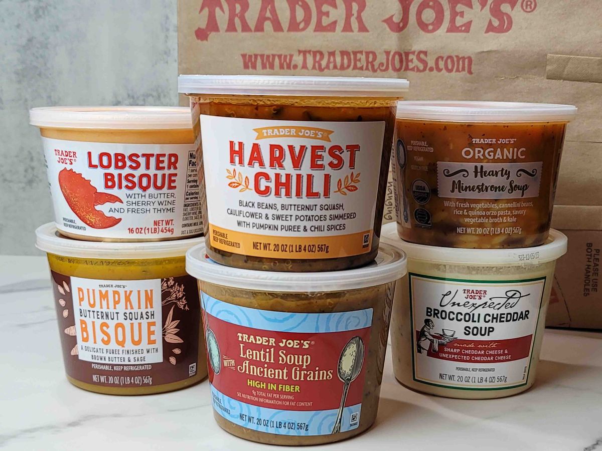 A selection of Trader Joe's refrigerated soups on a kitchen counter by a Trader Joe's shopping bag.