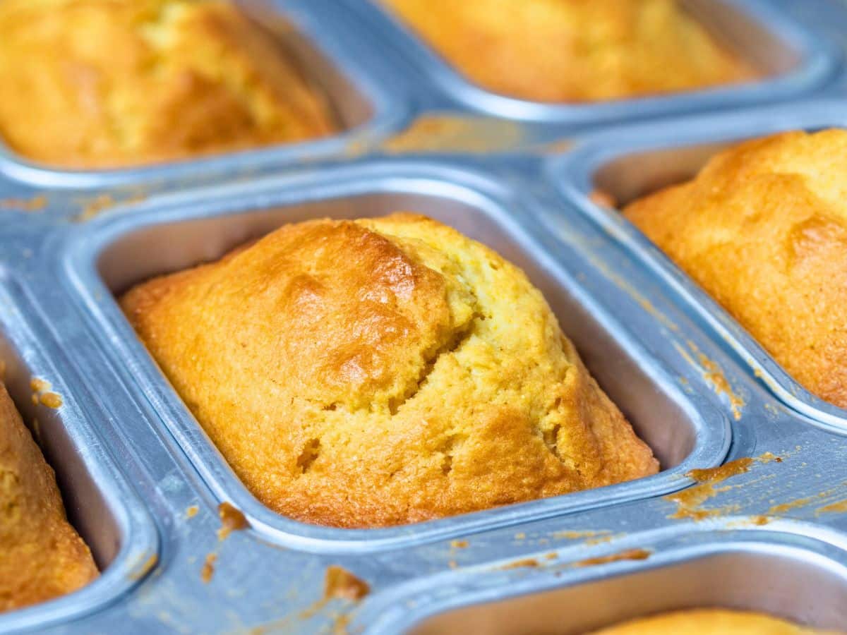 Freshly baked loaves of bread in a metal baking tray.