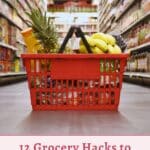 A shopping basket filled with groceries, including pineapples and bananas, placed in the aisle of a grocery store. The text reads: "12 Grocery Hacks to Slash Your Food Bill.