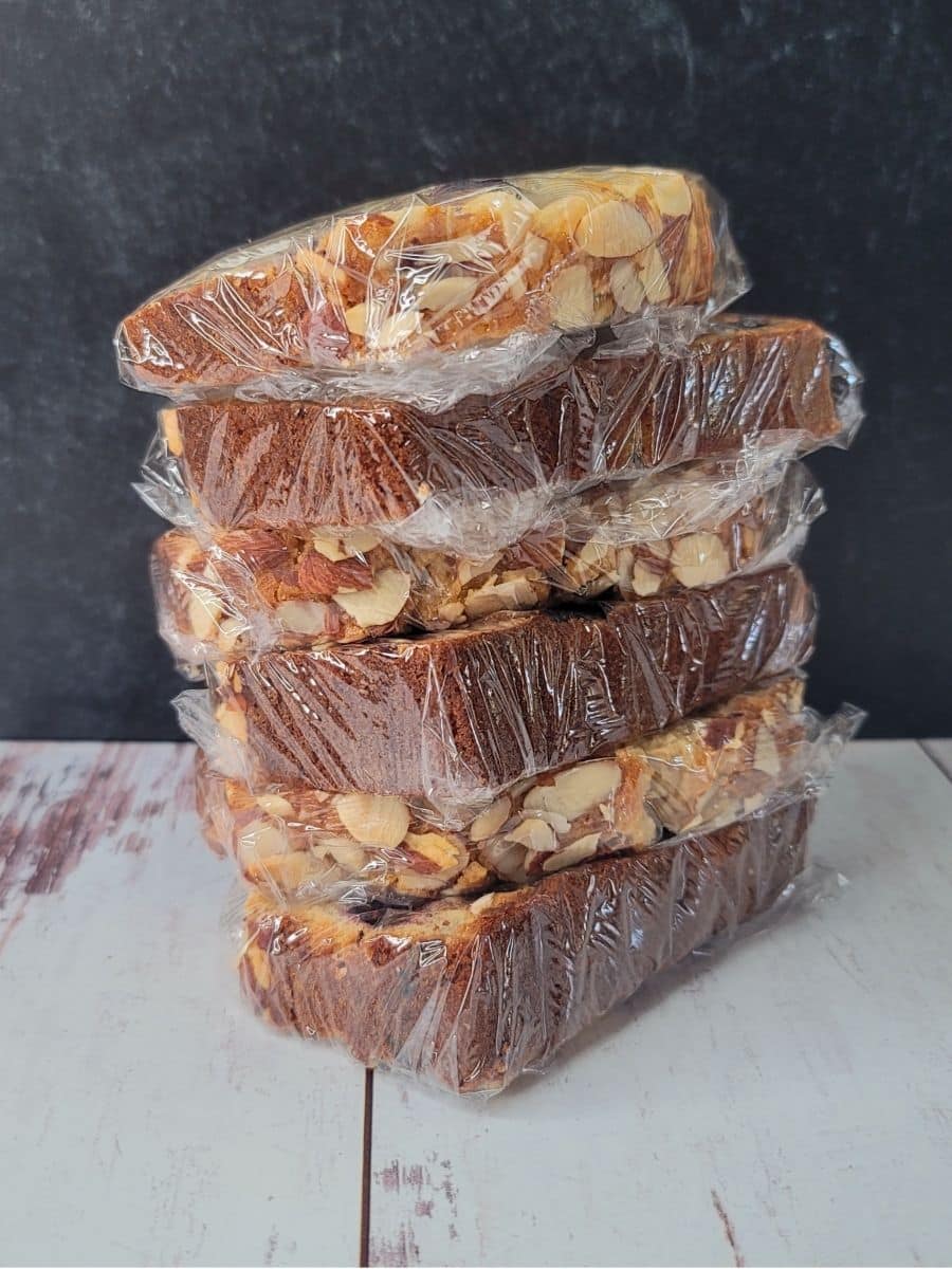 A stack of six slices of cherry bread wrapped in plastic and ready to freeze.