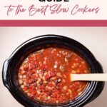A slow cooker filled with a chunky tomato-based bean stew, with a wooden spoon inside. Text above reads: "The Ultimate Guide to the Best Slow Cookers.