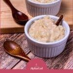 Two ramekins filled with creamy rice pudding on a wooden board, each with a spoon beside them. Text below reads: "Creamy Instant Pot Rice Pudding Recipe.