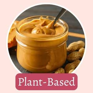 A jar of smooth peanut butter with a spoon inside, surrounded by peanuts. The text "Plant-Based" is displayed below.