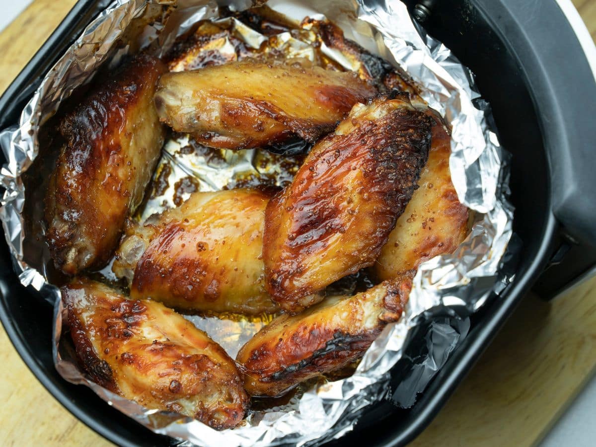 Chicken wings cooked in an air fryer, resting on aluminum foil.