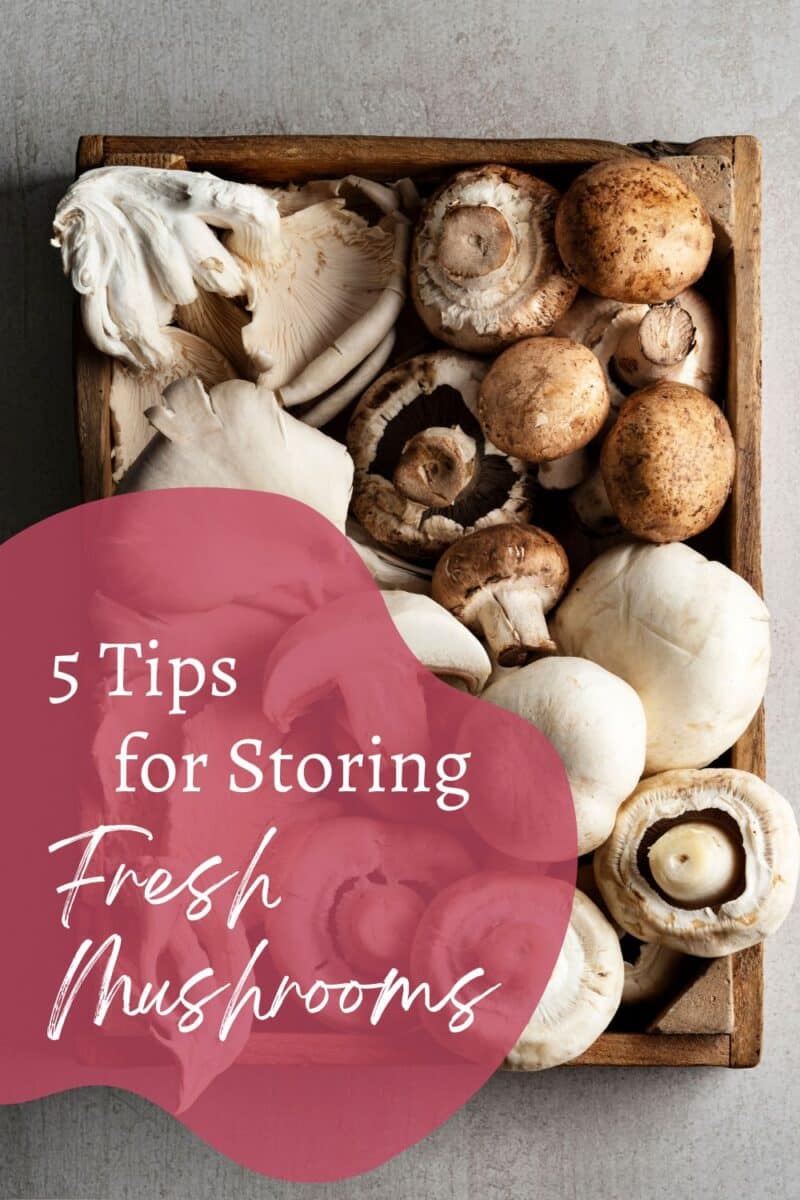 A wooden crate filled with various mushrooms, including button and oyster mushrooms. Text overlay reads, "5 Tips for Storing Fresh Mushrooms.