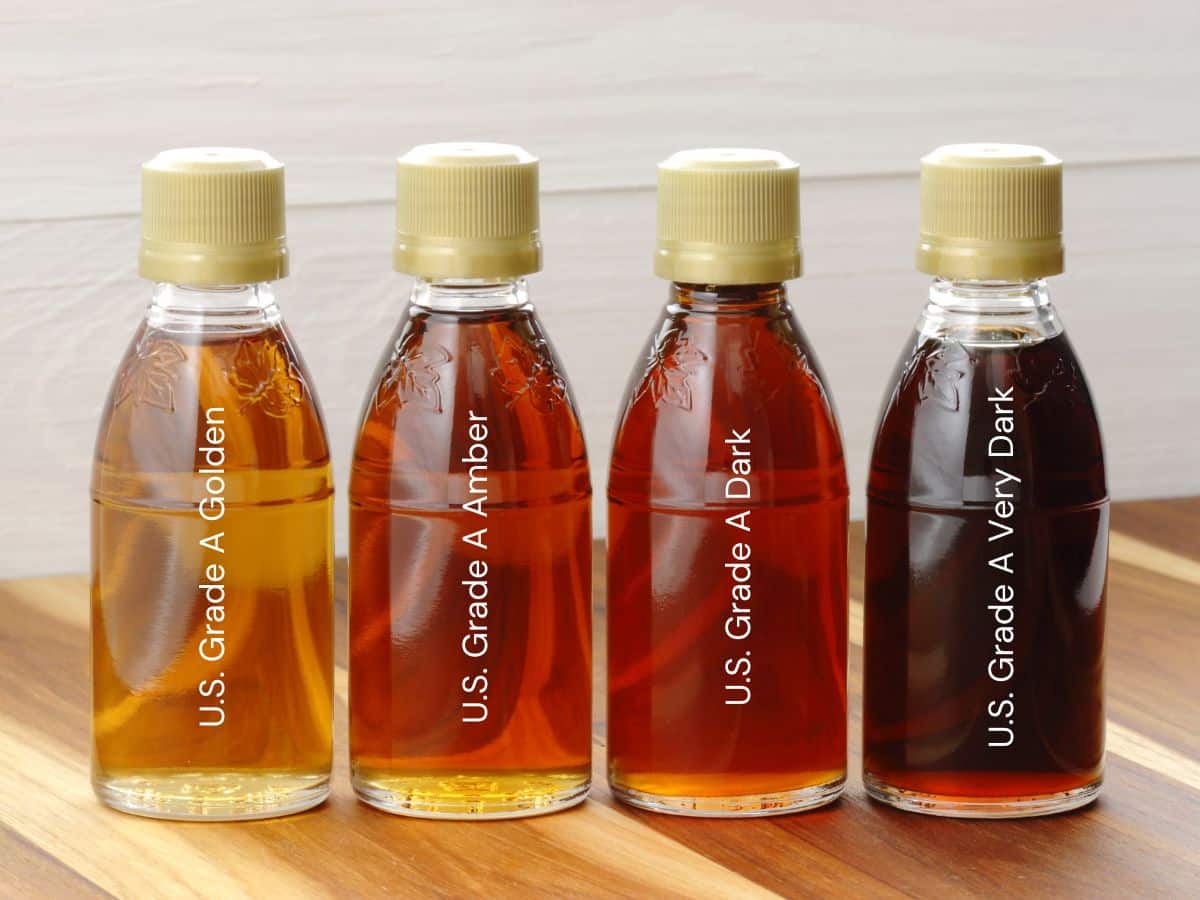 Four bottles of maple syrup labeled from left to right: U.S. Grade A Golden, U.S. Grade A Amber, U.S. Grade A Dark, and U.S. Grade A Very Dark, arranged on a wooden surface.