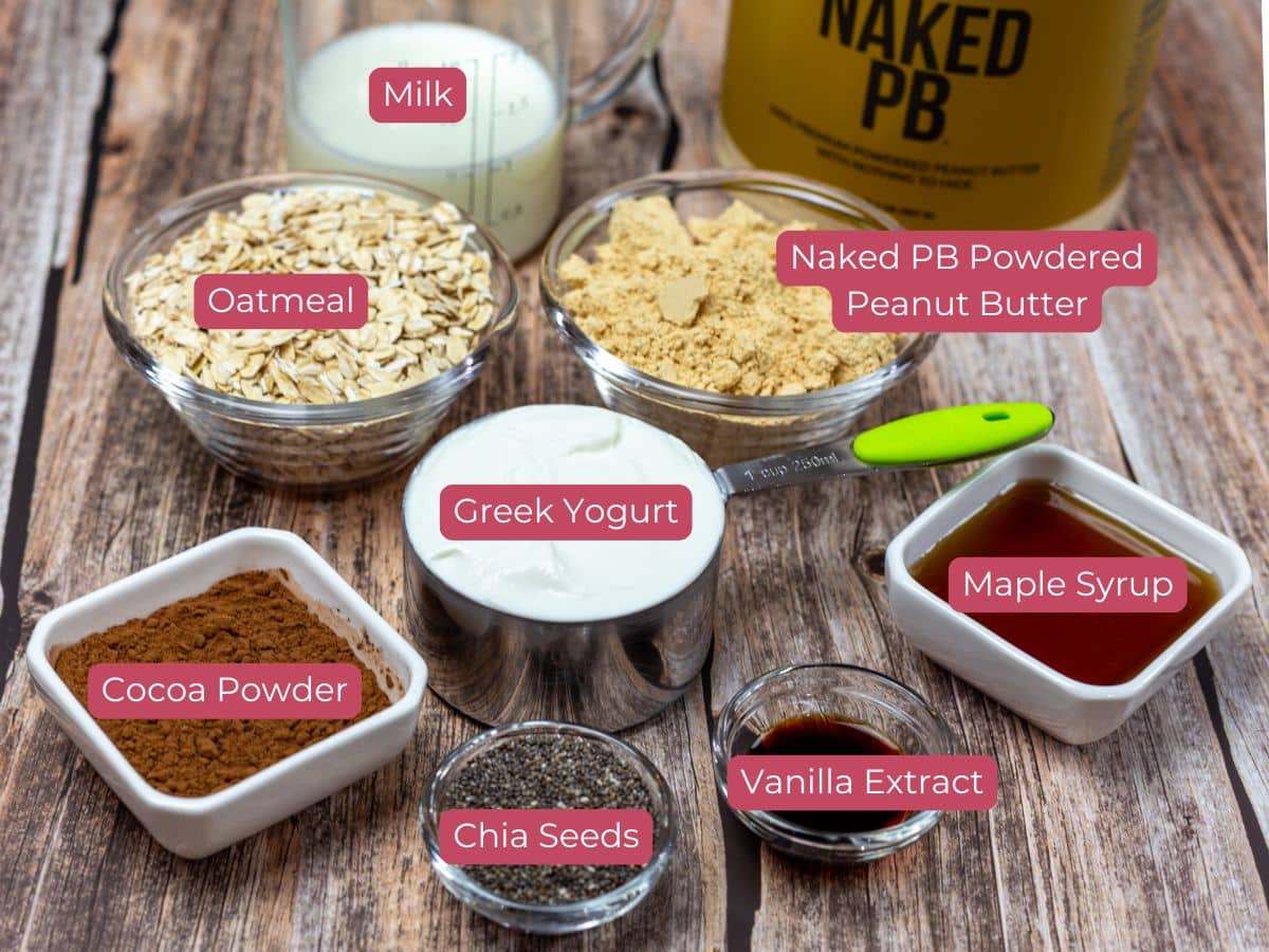 Ingredients for a recipe: milk, oatmeal, powdered peanut butter, Greek yogurt, maple syrup, cocoa powder, chia seeds, vanilla extract.