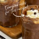 Three jars of chocolate dessert topped with coconut flakes and chocolate chips, placed on a wooden board. A spoon is on the table. Text on image reads: "Everyone asks for this recipe!.