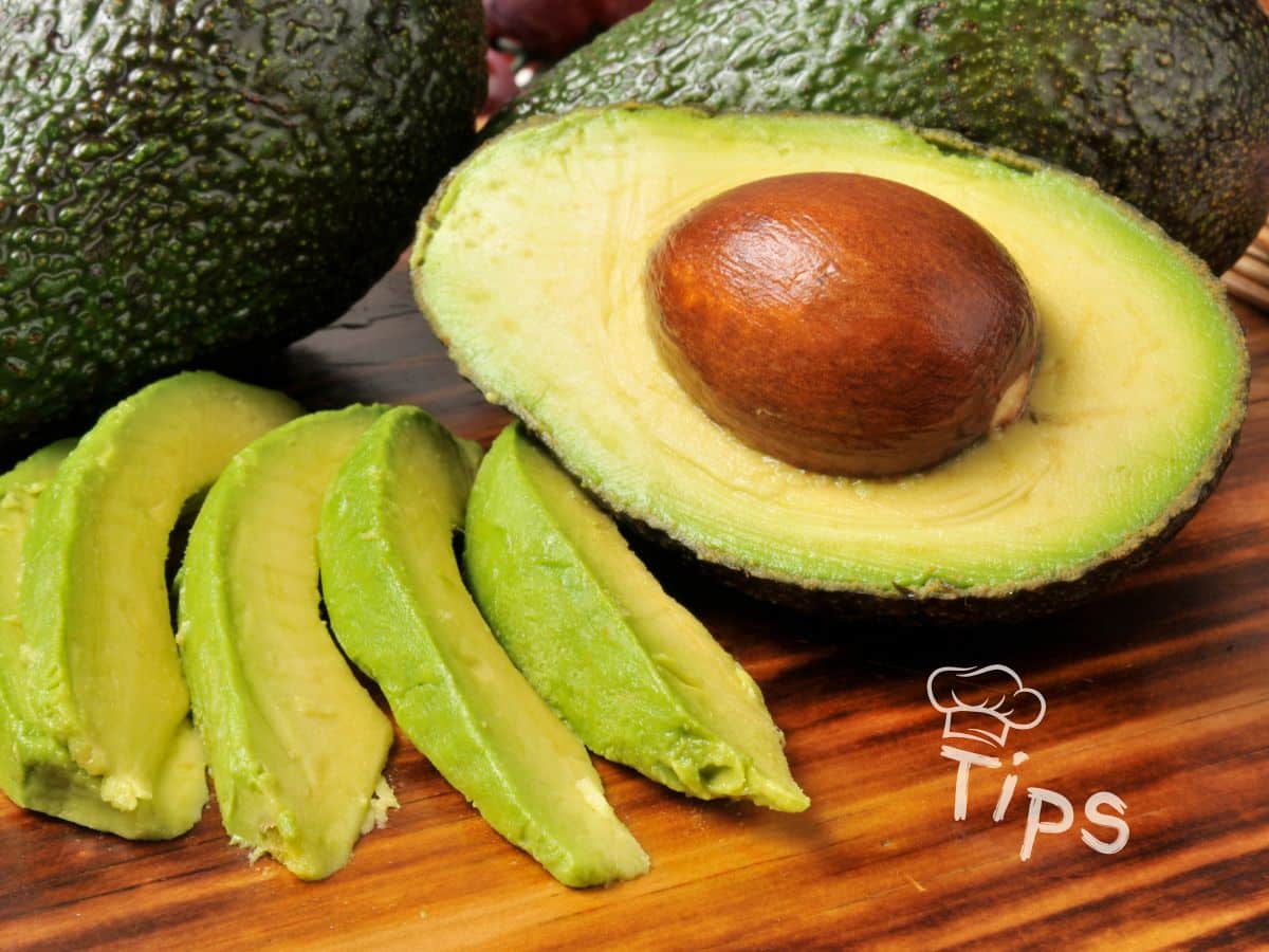 Sliced avocado on a wooden board with whole avocados in the background. Text reads "Tips" with a chef's hat graphic.