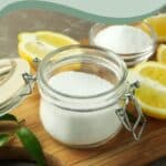 Open jar of salt, lemon halves, and leaves on a wooden cutting board, with text: "Keep Your Wooden Cutting Board Clean and Long Lasting.