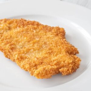 A piece of breaded, fried schnitzel on a white plate.