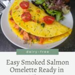 A plate with a smoked salmon omelette topped with tomato slices and herbs, served with a side salad. Text below reads: "Easy Smoked Salmon Omelette Ready in 15 Minutes. Dairy-free.