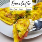 A fork holds a bite of smoked salmon omelette with fresh dill; a sliced omelette sits on a white plate behind it. Text overlay highlights it's dairy-free, easy, and savory.