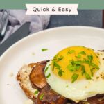 A slice of toast topped with sautéed mushrooms, a sunny-side-up egg, chopped parsley, and crumbled cheese on a white plate.
