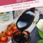 A spoon drizzles thick balsamic glaze over a jar, surrounded by cherry tomatoes, basil leaves, and a bottle of balsamic vinegar.