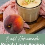 A glass of peach lassi topped with pistachio pieces sits on a wooden tray next to a fresh peach and a pink cloth; text reads, "Best Homemade Peach Lassi Recipe for Summer.